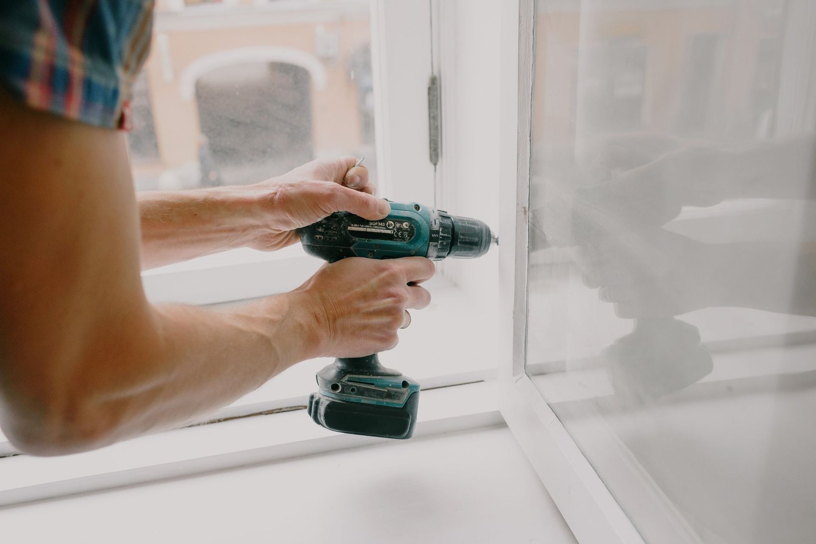 Maintenance worker adjusting a window frame during property upkeep in Manchester
